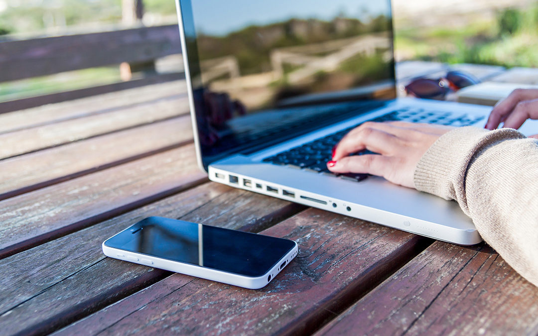 Person using laptop outdoors on wooden decking